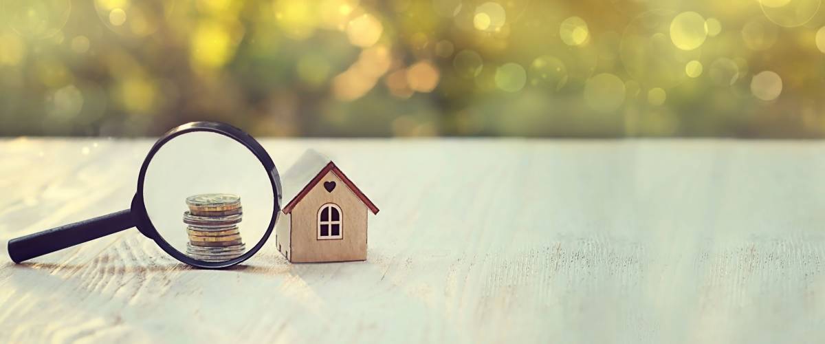 house and money. toy house, magnifying glass and coins. concept of mortgage