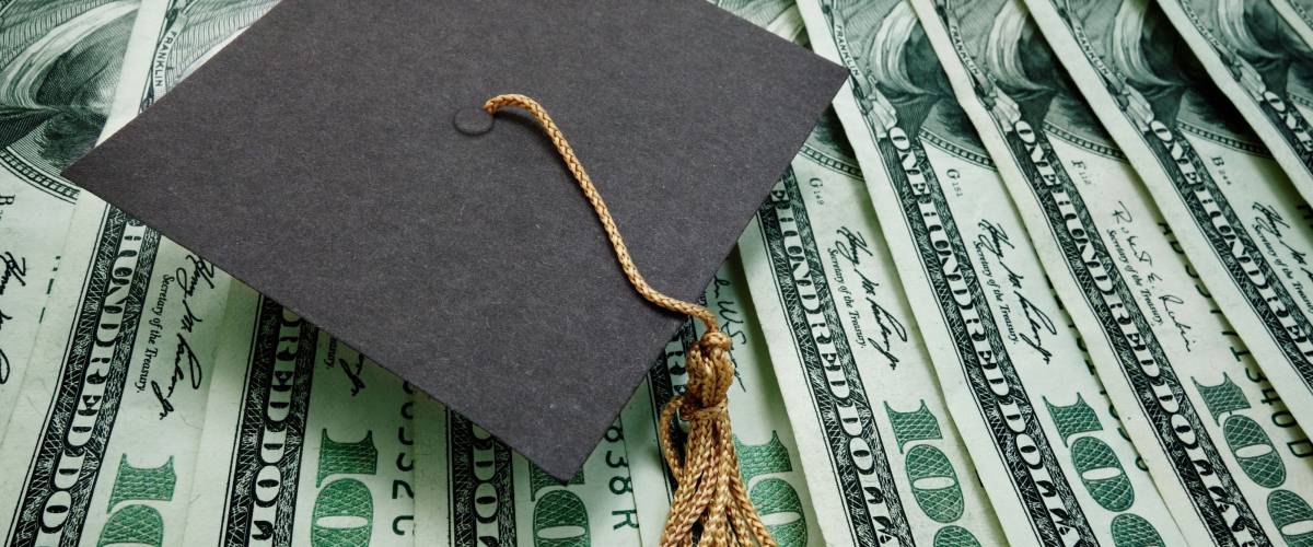 graduation cap on assorted hundred dollar bills - education concept
