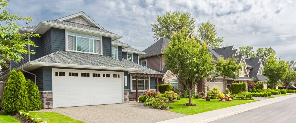 Nicely trimmed and manicured garden in front of a luxury house on a sunny summer day. Street of houses in the suburbs of Canada.