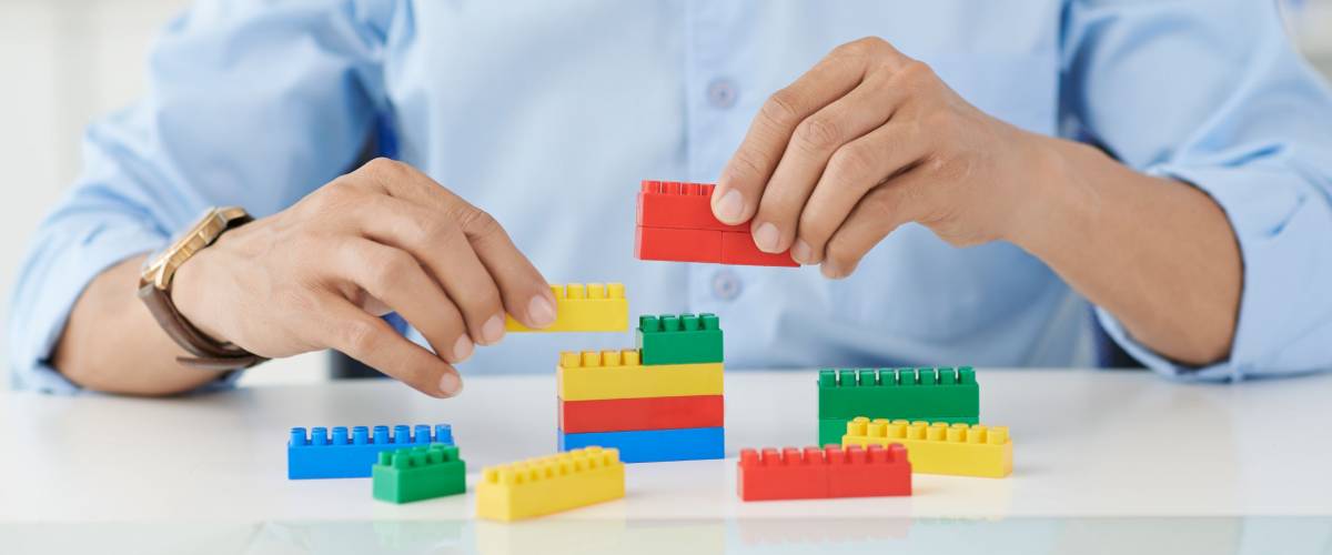Businessman connecting lego details at his place of work