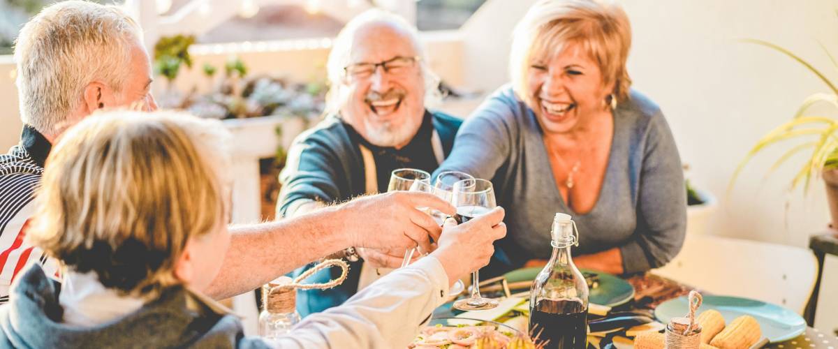 Group of happy senior friends cheering at barbecue meal in terrace outdoor, Maine