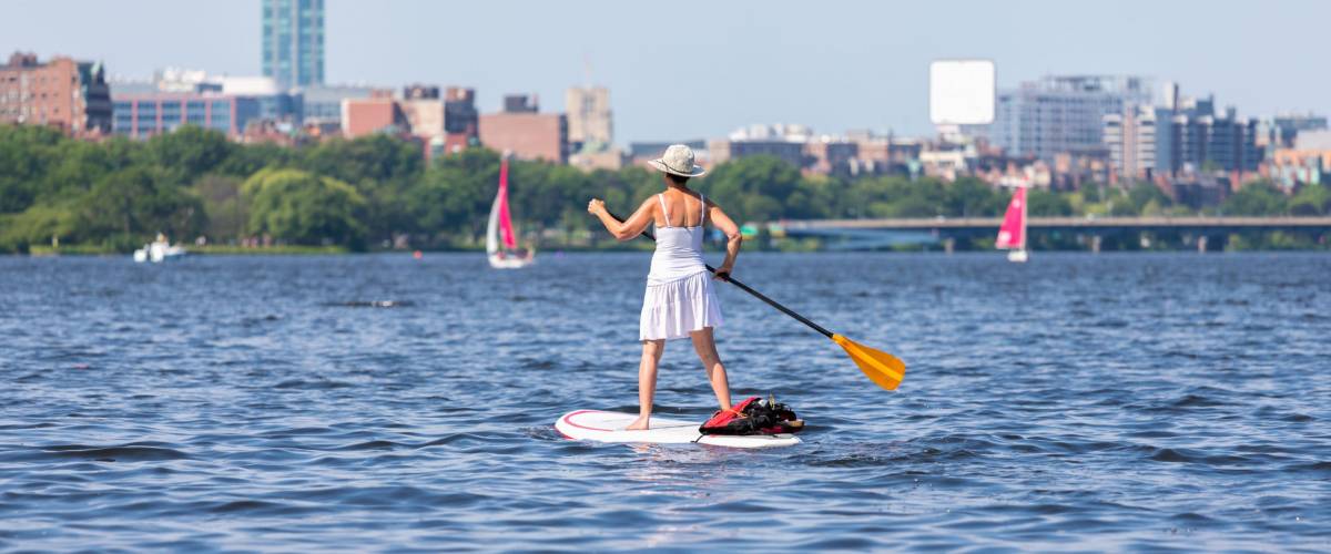 Old woman sailing on the Charles river on sunny day with happy on Boston city background.