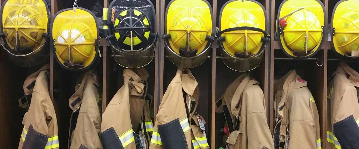 A lineup of firemen’s helmets and turnout gear in a locker at a volunteer fireman’s station