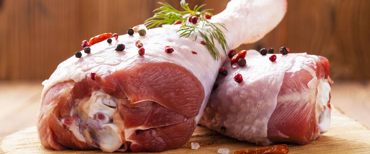 Raw turkey thigh with spices on a wooden board