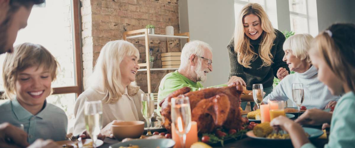 Photo of big full family reunion gathering sit feast dishes dinner table young wife giving old parents fresh bakery multi-generation in evening living room indoors