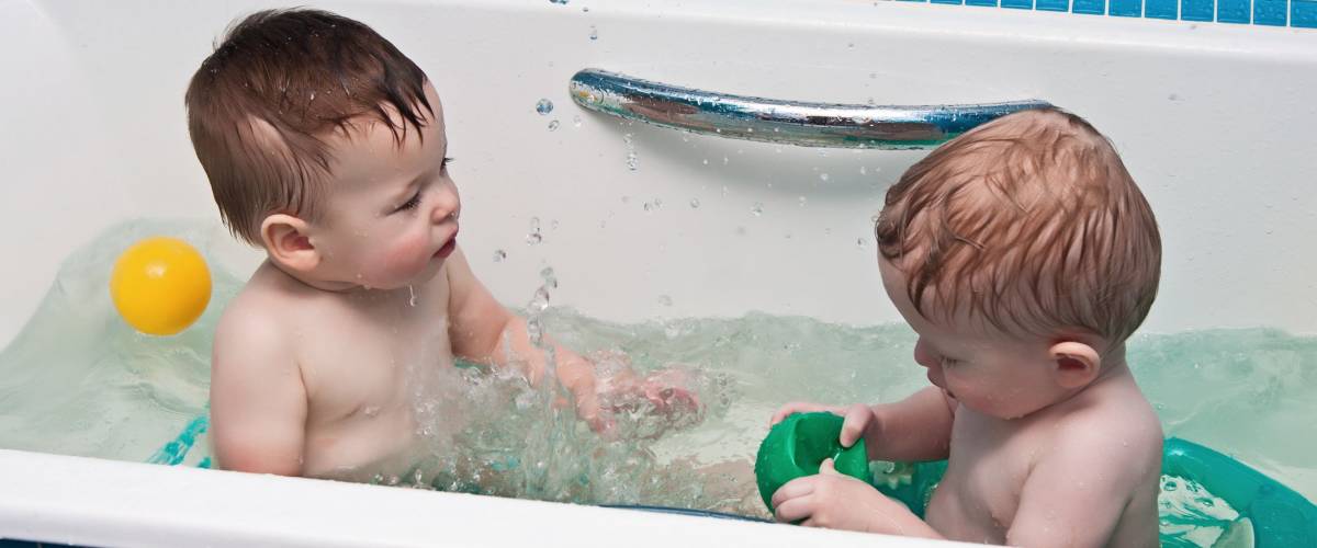 Two-year-old twins play a bathroom