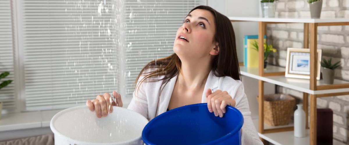 woman collecting rain from leaky house