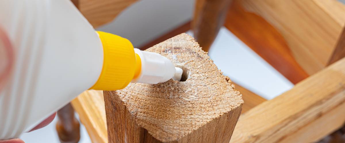 Person using glue to fix broken wooden furniture