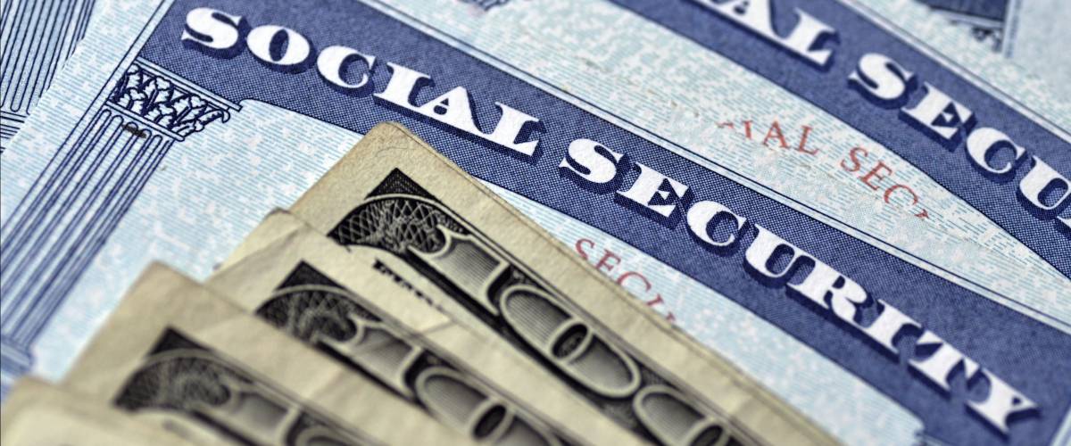 Detail of several Social Security Cards and cash money symbolizing retirement pensions financial safety