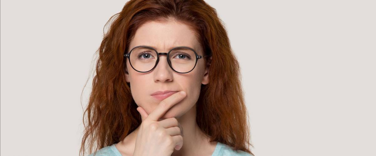 Pensive young red-haired young woman making a decision