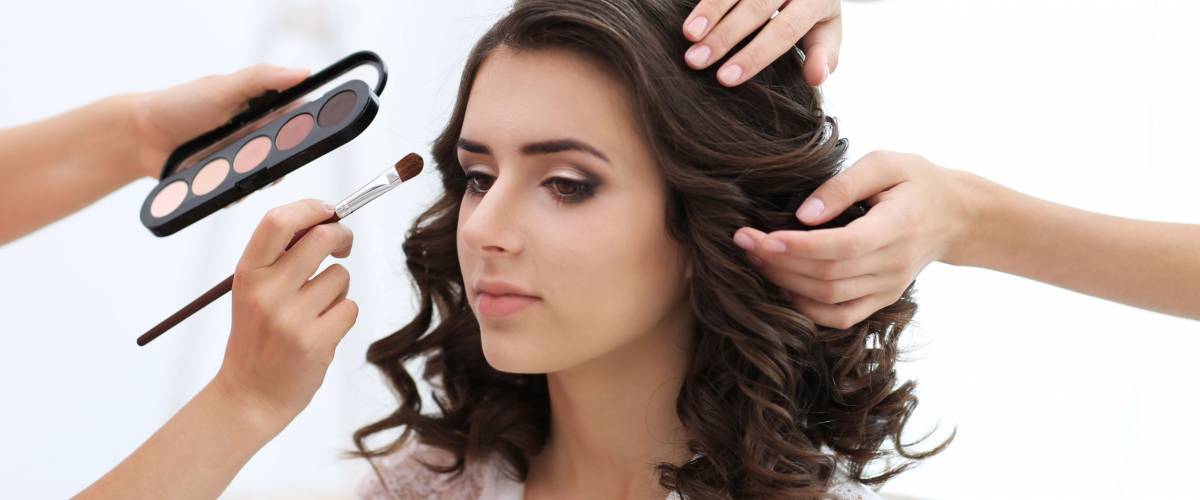 Makeup artist and hairdresser preparing bride before her wedding