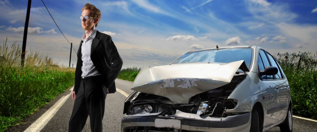 Young man standing outside his wrecked car.