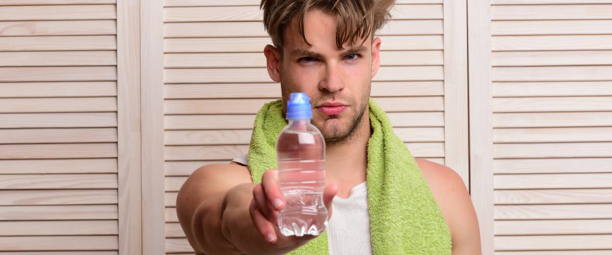 Young man apparently ready to shower with bottled water