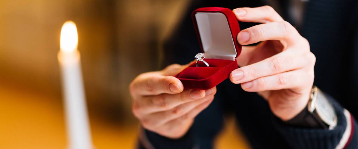 Male hands with red velvet box containing engagement ring with brilliant