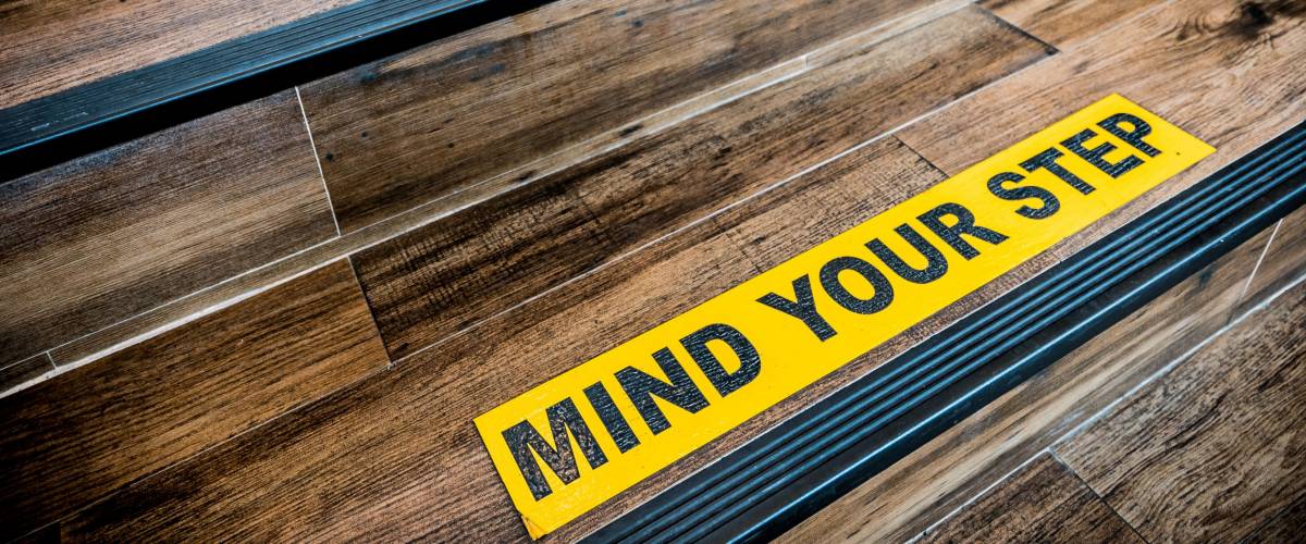 Mind your step sticker sign pasted on wooden stair. Warnings, abstract, or indoor architecture concept