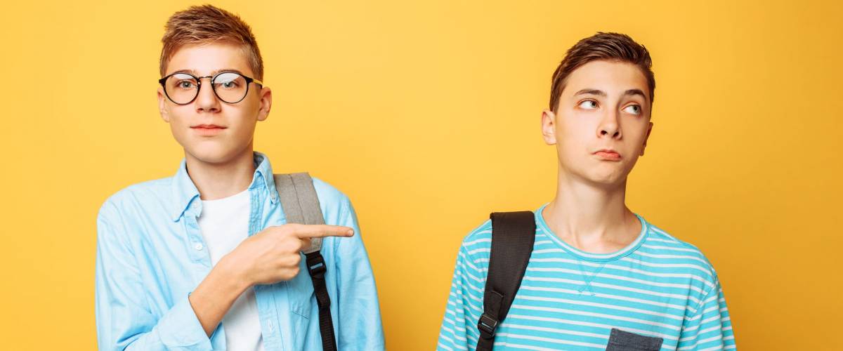 Two teen guys point at each other with their thumbs, blame and do not want to admit their guilt