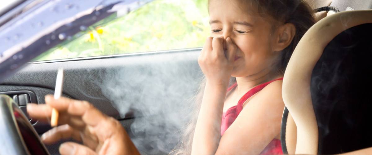Father smoking cigarette and the child choking of smoke in a car