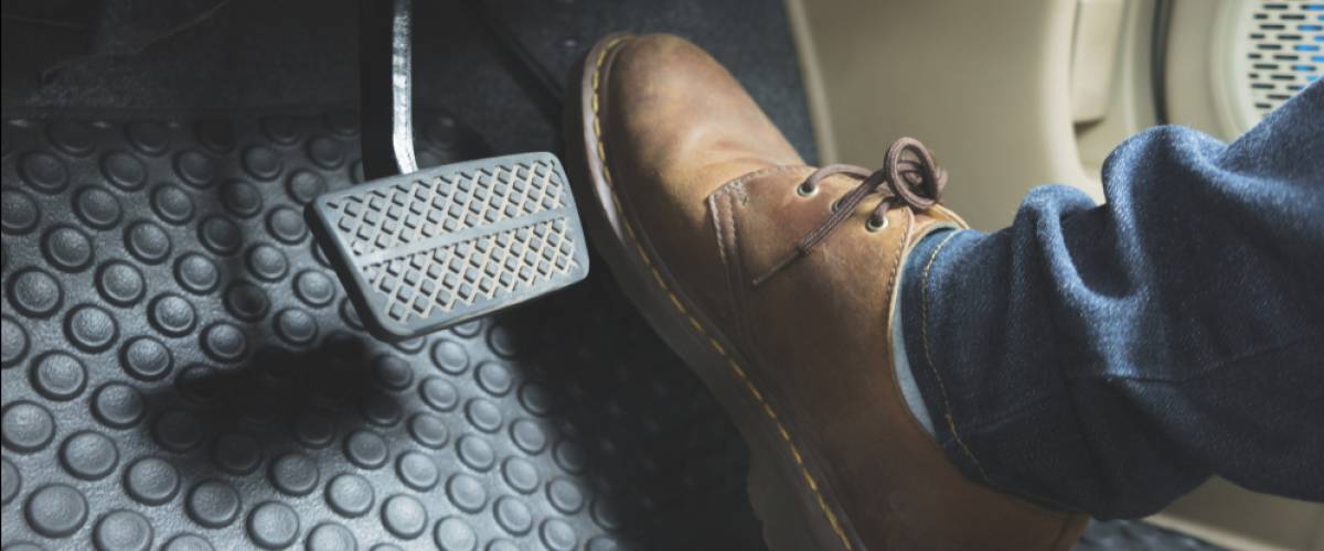 man's leather boot on foot pedal in car