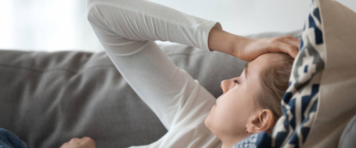 woman with headache laying on couch