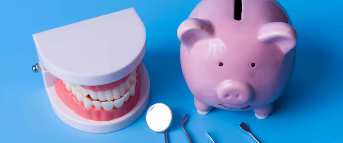 Piggy Bank on a blue background and dental instruments. The concept of saving money for the manufacture of dental implants and treatment.