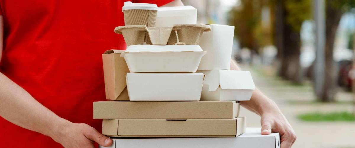 Diverse of paper containers for takeaway food. Delivery man is carrying pizza, Chinese noodles, burgers and coffee.