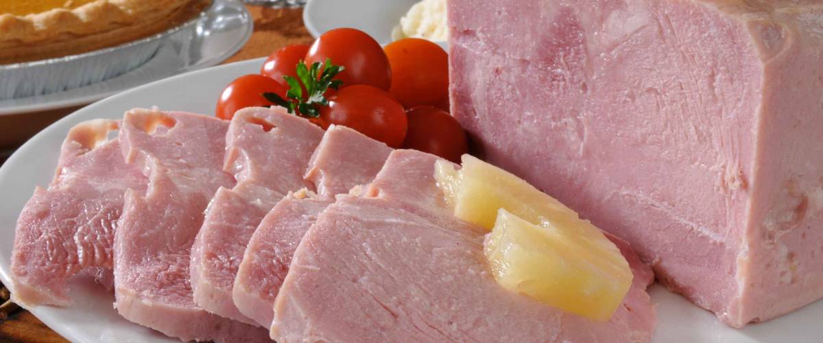 A sliced ham with pineapple and pumpkin pie