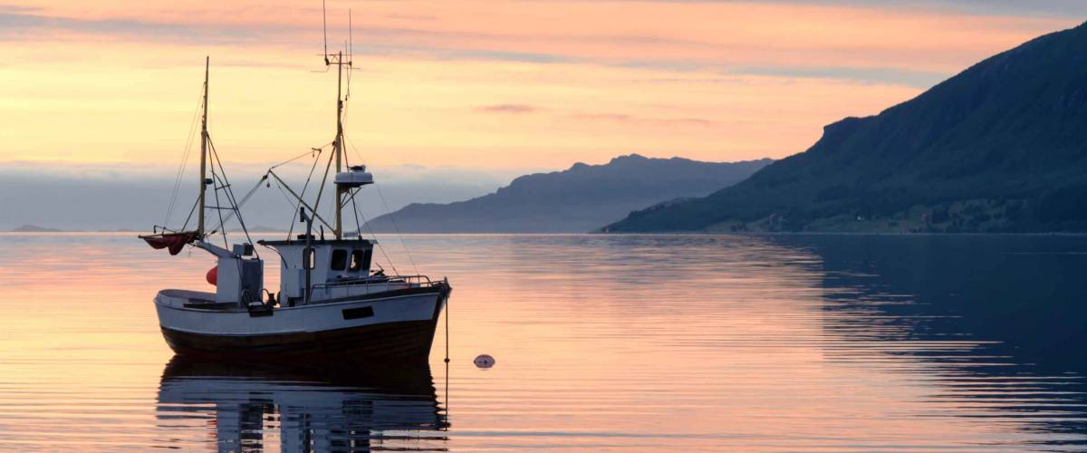 a fishing boat lies at sundown in the fjord