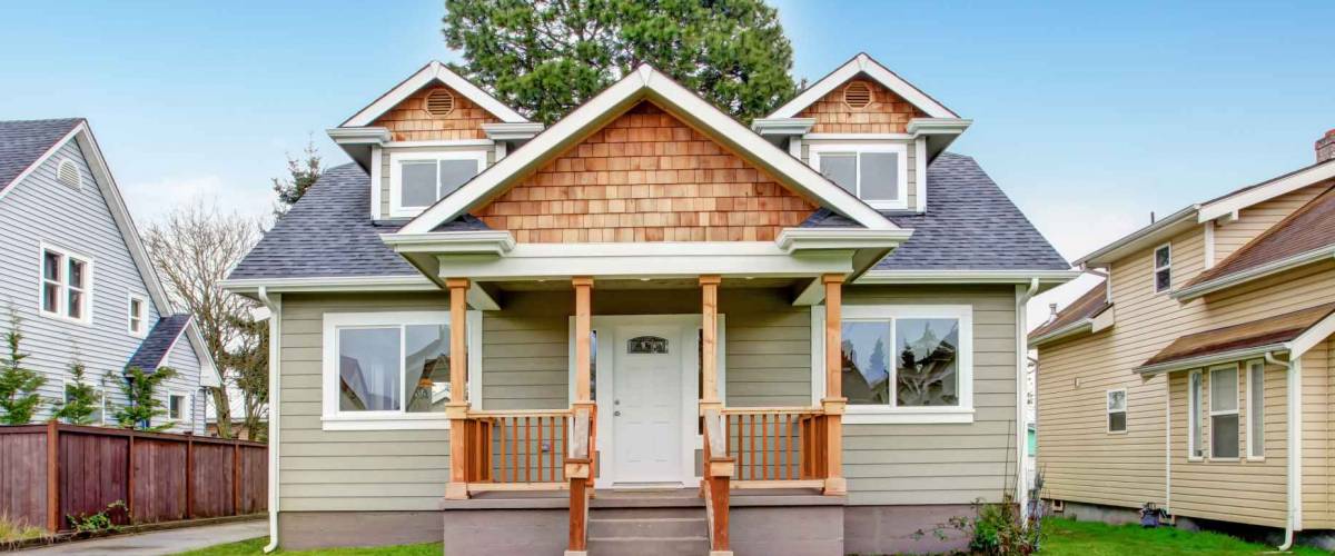 Small house with wooden column porch. View from walkway