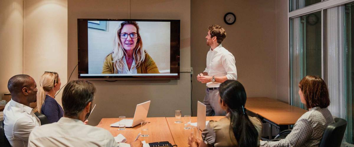 Group of business people having a late night video conference meeting. Sitting around a conference table talking and networking.