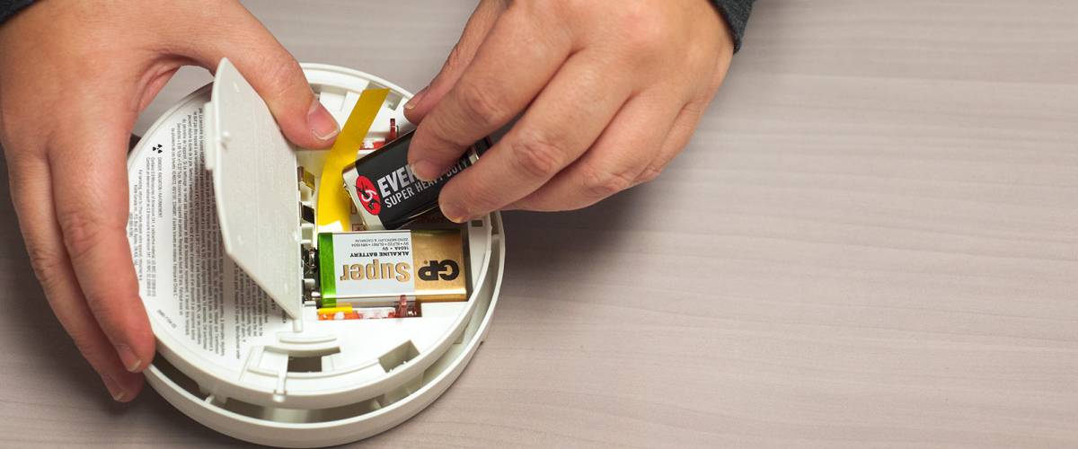 A man changes the battery in his smoke detector