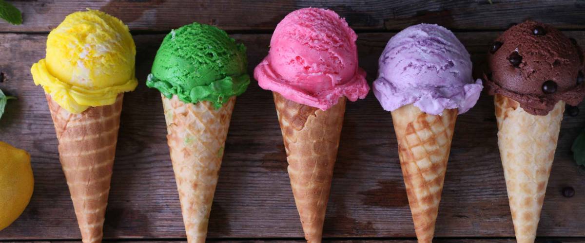 Variety of ice cream cones on wooden table.