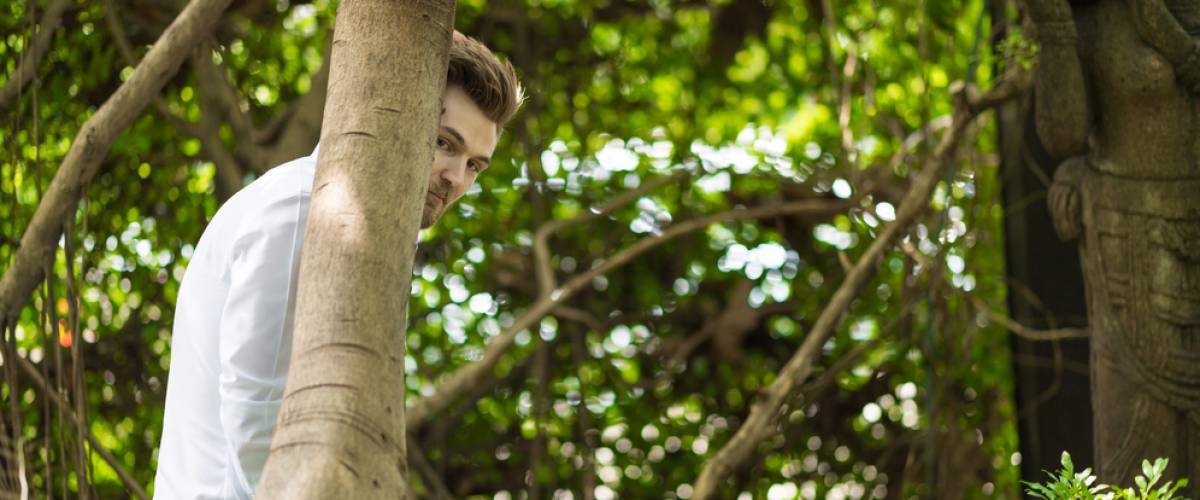 Man hiding behind tree