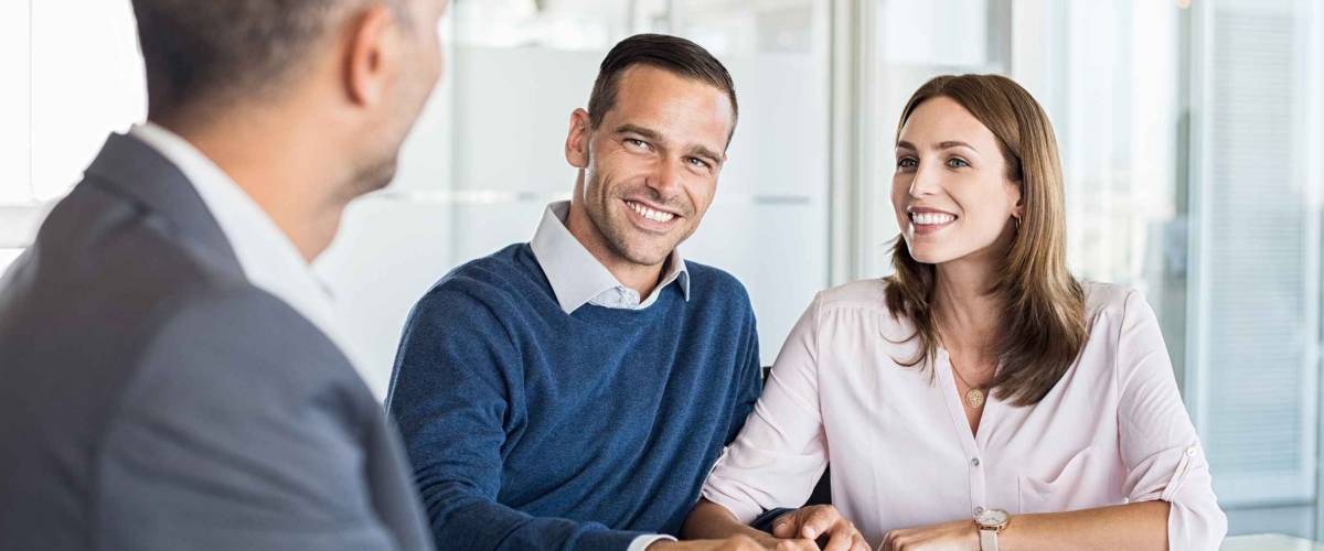 Mature financial advisor showing report to young couple for their investment. Salesman and positive couple talking about purchase. Happy couple consulting financial agent for loan.