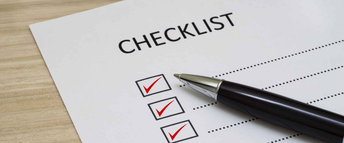Checklist concept - checklist box with red checkmark, paper and a pen with checklist word on wooden table