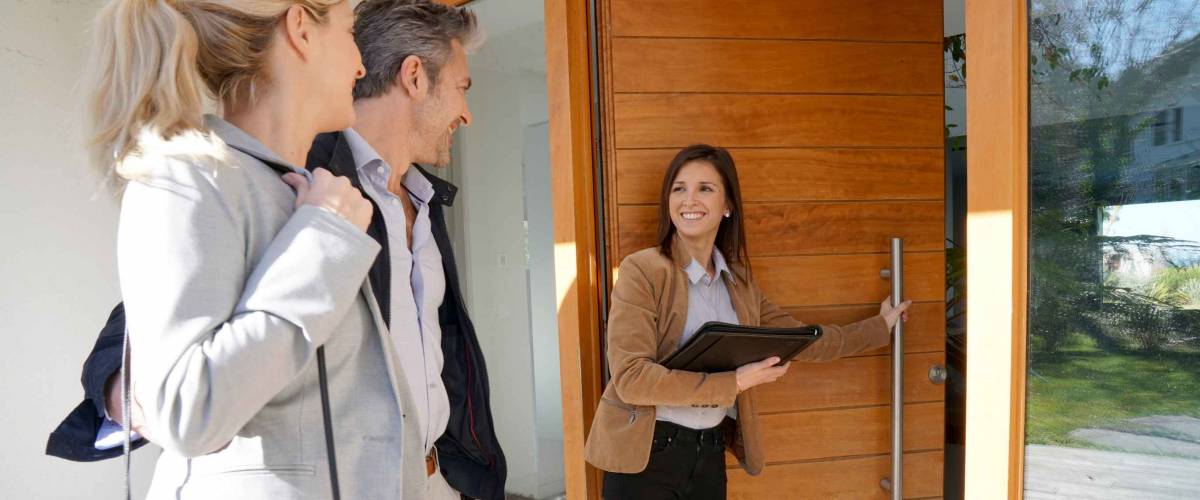 Real estate agent inviting couple to enter house for visit