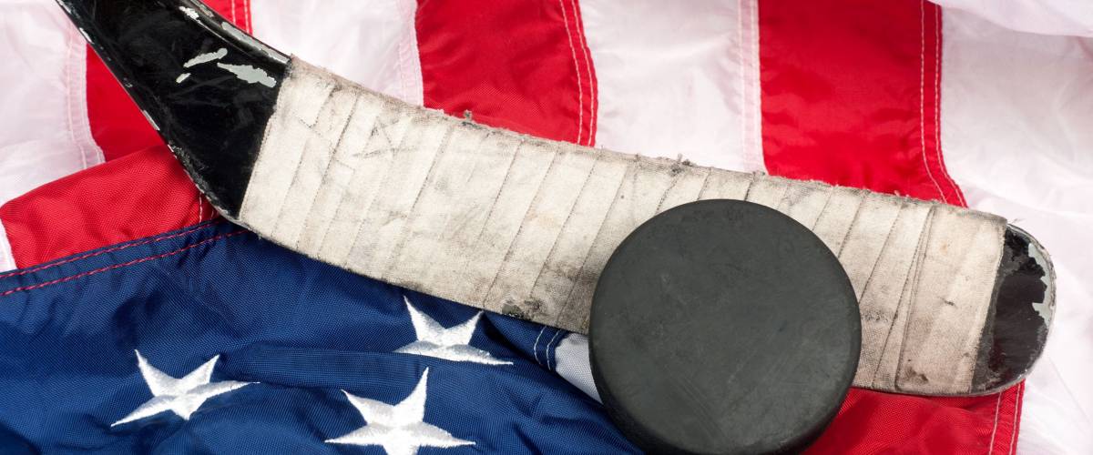 Hockey equipment including a stick and puck on an American flag to infer a patriotic American sport.