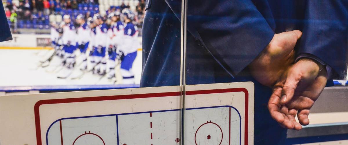 coach on the ice hockey bench with tactic board looking at player after hockey match.