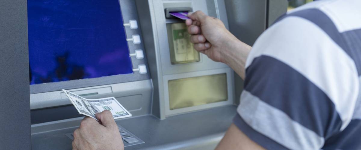 Man taking money from a cash machine using credit card. Cash widrow and finance concept