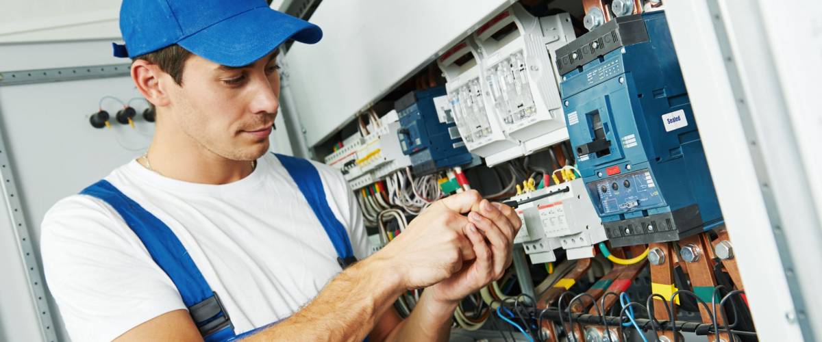Young adult electrician builder engineer screwing equipment in fuse box