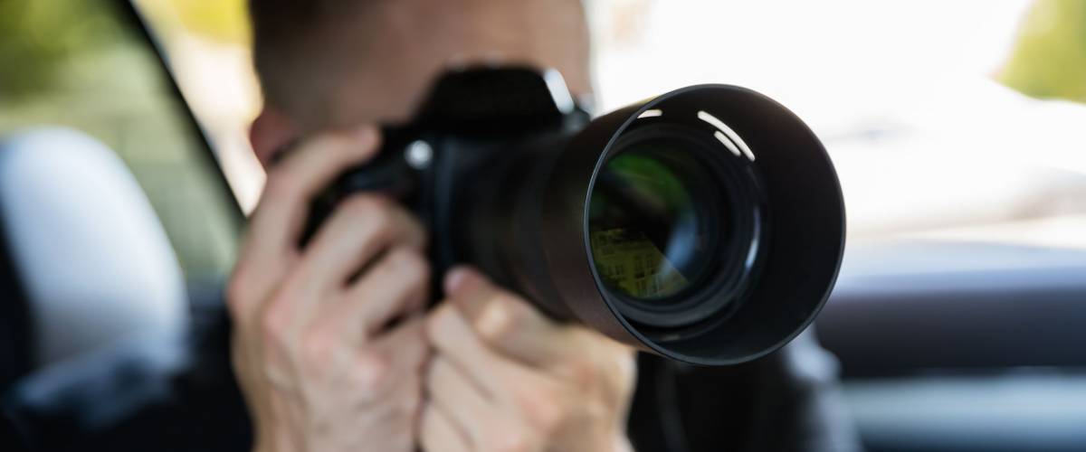 Private Detective Sitting Inside Car Doing Surveillance Work Photographing With Camera