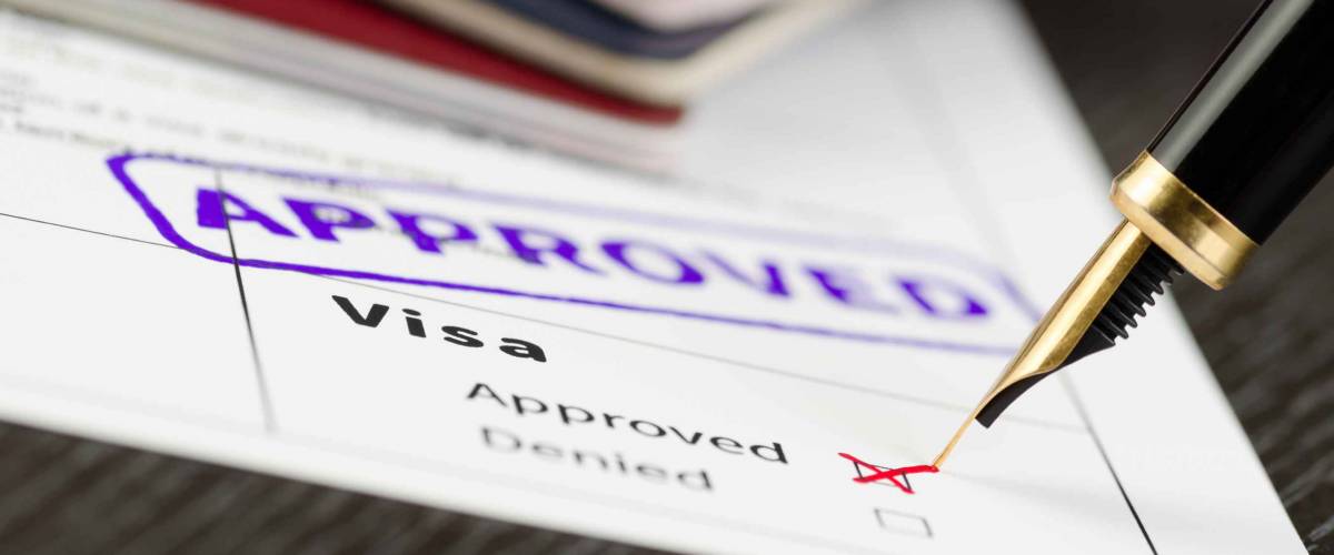 Visa form close up, fountain pen and approved stamped on a document.