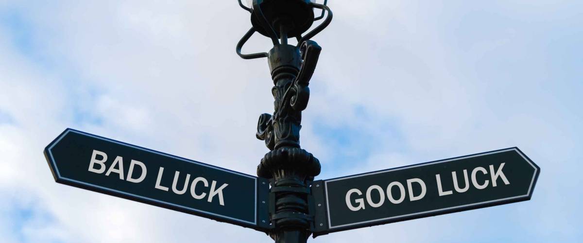 Street lighting pole with two opposite directional arrows over blue cloudy background. Bad Luck versus Good Luck concept.