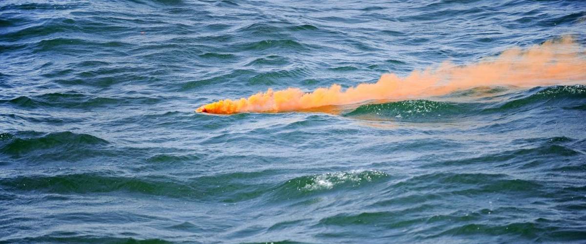 Orange smoke comes out from a flare fired during a safety demonstration drill on the sea