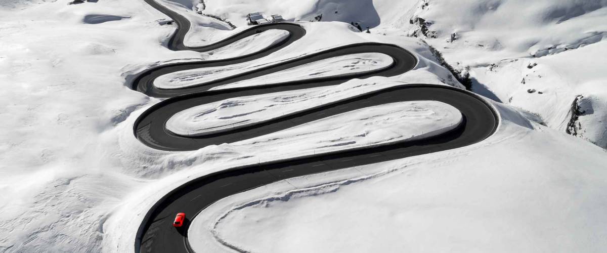 Aerial view of a red car traversing Julier Pass in the Swiss Alps