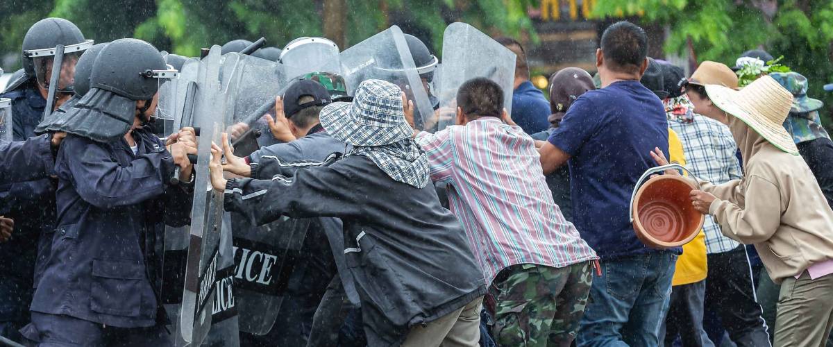Special police unit with shields against protesters,Protester Pushes Police Riot Shields at a Political Rally.
