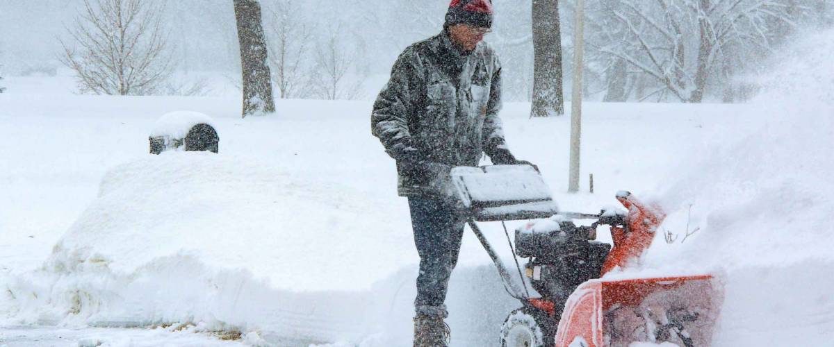 Man with earphones snowblowing during a blizzard