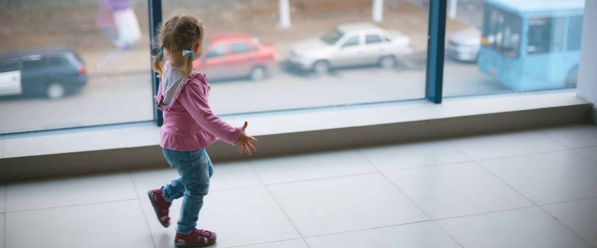 a little girl runs around the new large apartment near a panoramic window