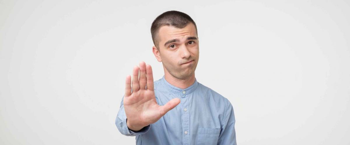Young man showing stop gesture. Concept of deny. Say no to wrong decision