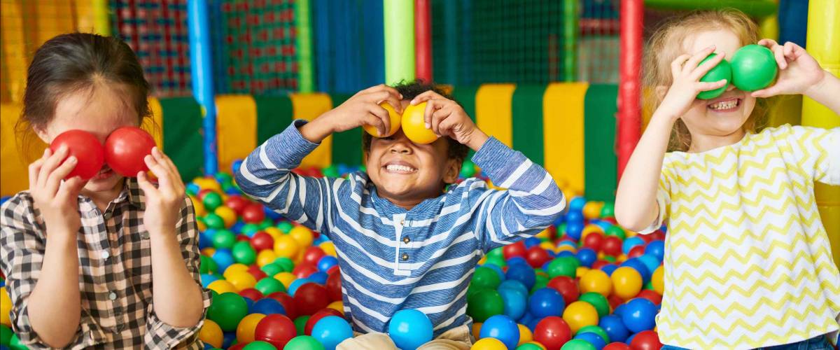 Portrait of three funny little kids playing in ball pit and enjoying time in childrens entertainment and play area, copy space