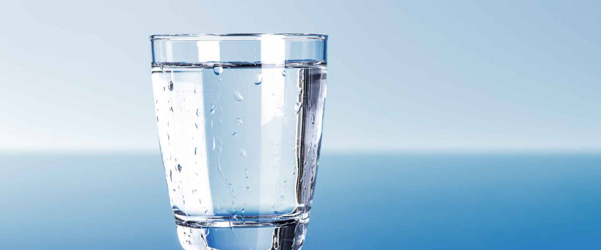 Drinking water in glass on blue